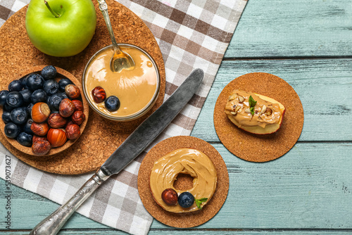 Composition with tasty nut butter, apples, hazelnuts and blueberry on color wooden background