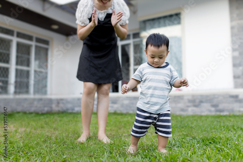 Εκτύπωση καμβά The first step little baby learning to walk with a happy mother in the front yard