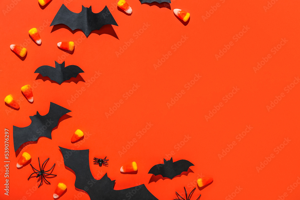 Frame made of paper bats, spiders and candy corns on red background Frame made of paper bats, spiders and candy corns on red background