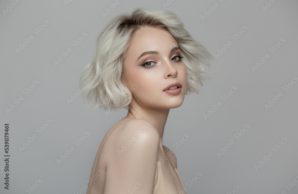 Portrait of a beautiful blonde girl with a short haircut. Gray background. - obrazy, fototapety, plakaty 