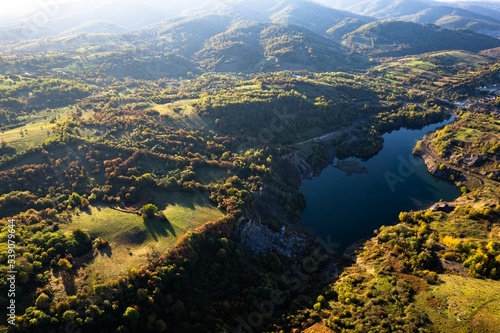 Aerial view of a small lake at sunset, that formed in a former coal mine exploitation, near Resita city, Romania. Captured with a drone, from above, in autumn setting. 