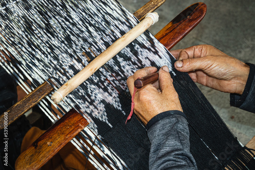 Close up of traditional weaving technique IKAT for making scarfs or Makana (macana) or other fabric by hand with cotton threads. Design are traditional for Gualaceo canton, Azuay province, Ecuador	 photo