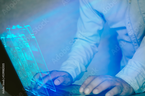 A young man uses a computer and the Internet to check and analyze the market direction, using futuristic HUD in a computer software for digital data