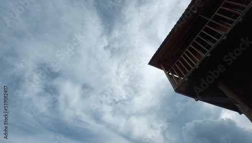 A view of a traditional house, made of wood with a beautiful iconic blue foggy sky.
