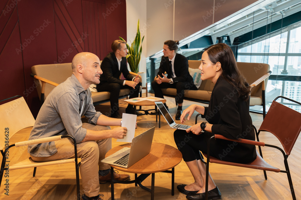 man and woman working together with two businessman discussing at background. businesswoman using laptop in workplace. colleague man and woman working in modern office man and woman working together with two businessman discussing at background. businesswoman using laptop in workplace. colleague man and woman working in modern office