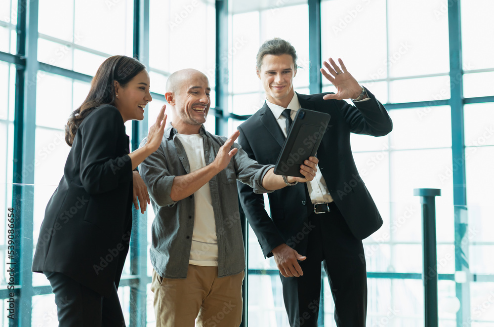 businessman and businesswoman happy greeting online to collegue on tablet in workplace with window background. colleague man and woman working in modern office businessman and businesswoman happy greeting online to collegue on tablet in workplace with window background. colleague man and woman working in modern office