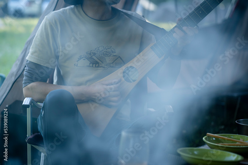 トラベルギターを弾いてキャンプを楽しむ男性 photo