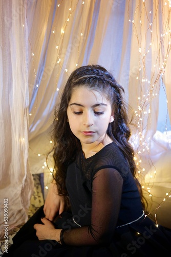 a girl dressed in a dress sitting in a room with Christmas decoration © Fotoproff
