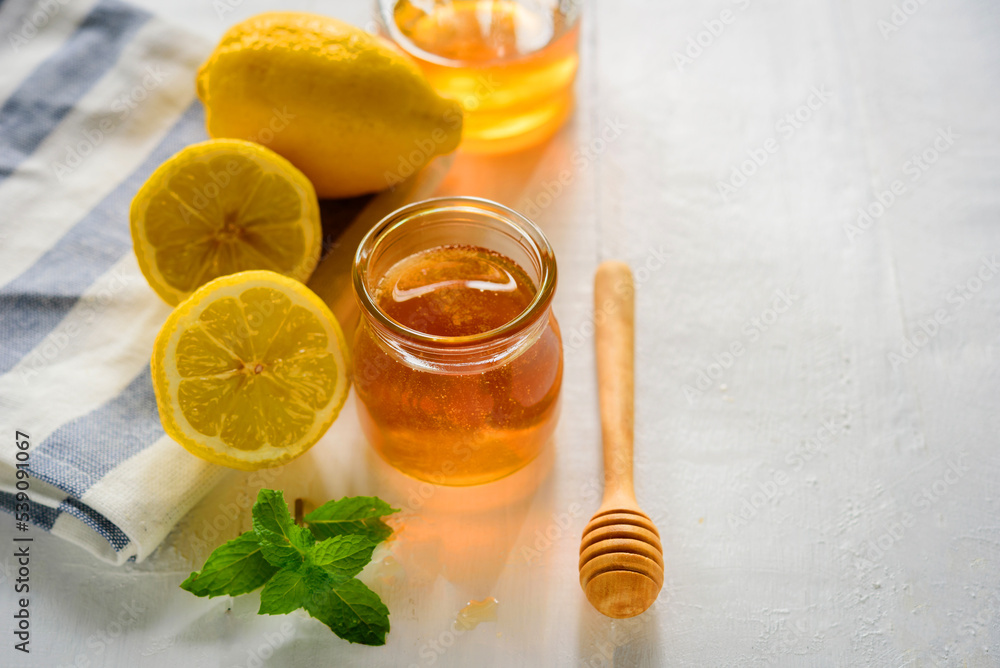 Honey with fresh lemon on wooden table background, honey dipper Honey with fresh lemon on wooden table background, honey dipper