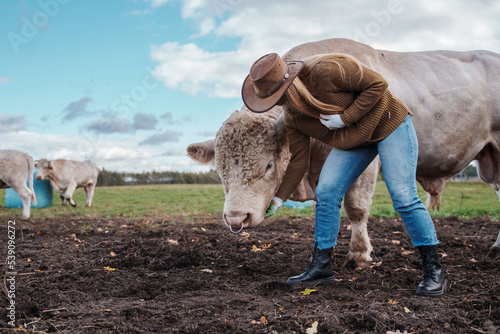 Fotografiet Shot of female breeder with cows in meadow in farm
