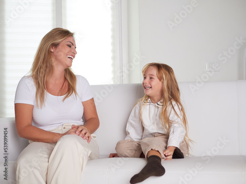 Young beautiful mother playing with daughter in livingroom © Stocked House Studio