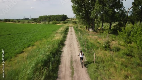 Radfahrerin von hinten fährt einen Feldweg entlang