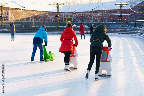 Winter rink. Girls on skates ride on ice. Active family sport during kids christmas winter holidays. School sports clubs. photo
