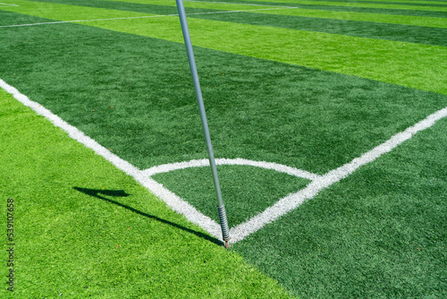 Field markings with corner flag and touchline on the football field with green tab grass.