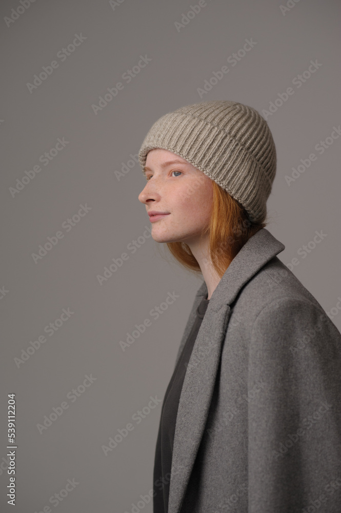 Fototapeta premium young girl model in beige hipster hat and coat isolated on light background. Product photo mockup for fashion brands and marketplaces, woolen cap, turkish textiles.
