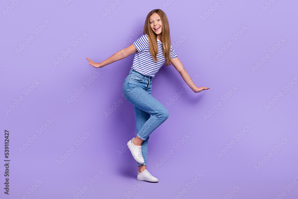 Full length photo of sweet cheerful small schoolgirl wear striped t-shirt smiling having fun isolated purple color background