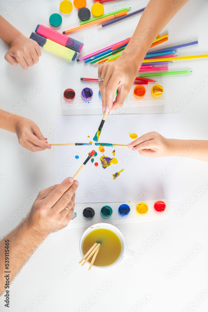 Humans hand of mother father and children is drawing with colorful pencils. Kids learning painting. Top view to white table with art supplies. Humans hand of mother father and children is drawing with colorful pencils. Kids learning painting. Top view to white table with art supplies.