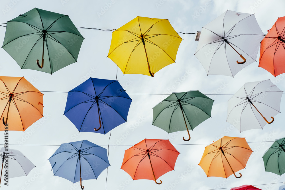 Many colorful umbrellas background. Opened umbrellas in the sky. Urban decoration. Bottom view. Many colorful umbrellas background. Opened umbrellas in the sky. Urban decoration. Bottom view.
