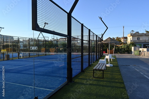View on enclosed court for padel with construction created by mesh and the glass back walls. Padel is a racket sport played in doubles and is similar to tennis with the same rules of scoring. photo
