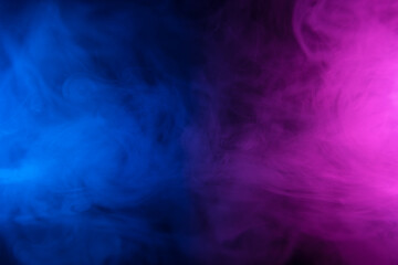 Clouds of colorful smoke in blue and purple neon light swirling on black table background with reflection