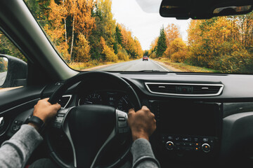 Man driving car on the country road in autumn.
