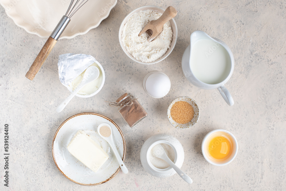 The concept of home baking. Ingredients for making dough, cake, cupcakes: eggs, flour, butter, cinnamon, milk, sugar on a light background. The concept of home baking. Ingredients for making dough, cake, cupcakes: eggs, flour, butter, cinnamon, milk, sugar on a light background.