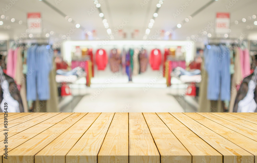 Obraz premium Empty wood table top with blur clothing boutique display interior shopping mall background