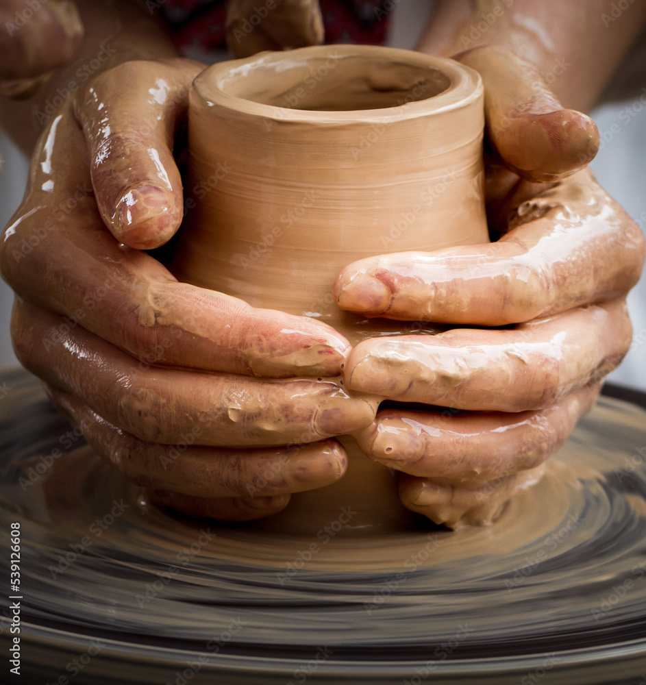 Close-up view of master working on pottery wheel and making clay pot
