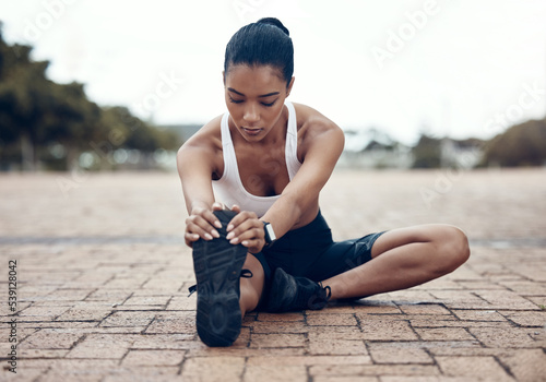 Fitness, sports and woman stretching legs in warm up to start training, exercise and cardio workout in Lisbon. Runner, Athlete and flexible girl holding running shoes for a healthy hamstring stretch photo