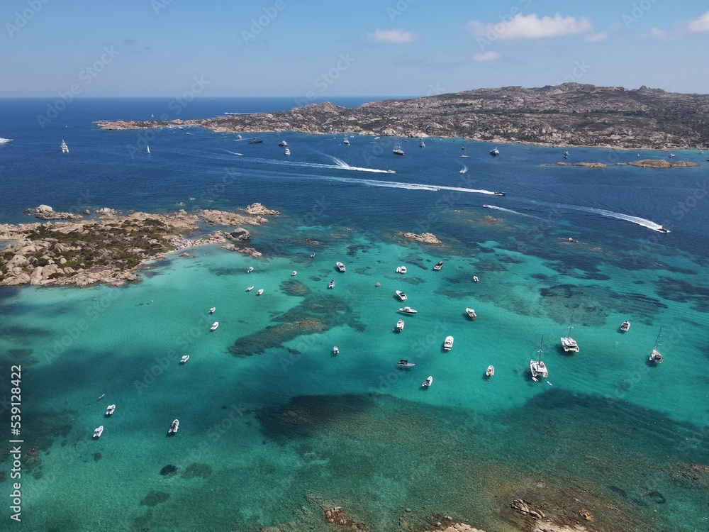 Aerial view of La Maddalena Island, Isola Giardinelli with the drone view of Caprera Island in Sardegna, Italy. Birds eye view of crystalline and turquoise water in north Sardinia, luxury yacht, boat.