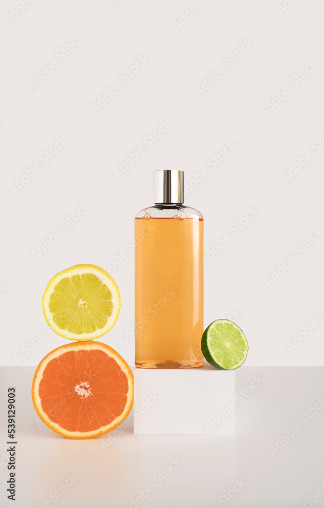 Shampoo or shower gel on a square podium, next to an orange, lemon and lime Shampoo or shower gel on a square podium, next to an orange, lemon and lime