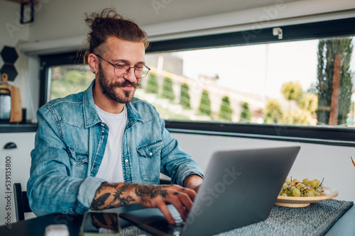 Canvas-taulu Young business man working at home with laptop and papers on desk