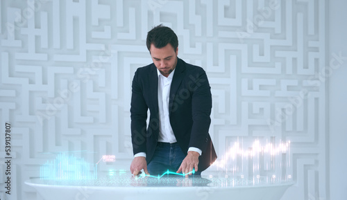 Successful businessman uses futuristic table with charts holograms of financial statistic, make investments, evaluate economic indicators. Internet of Things, science and innovation of technology.