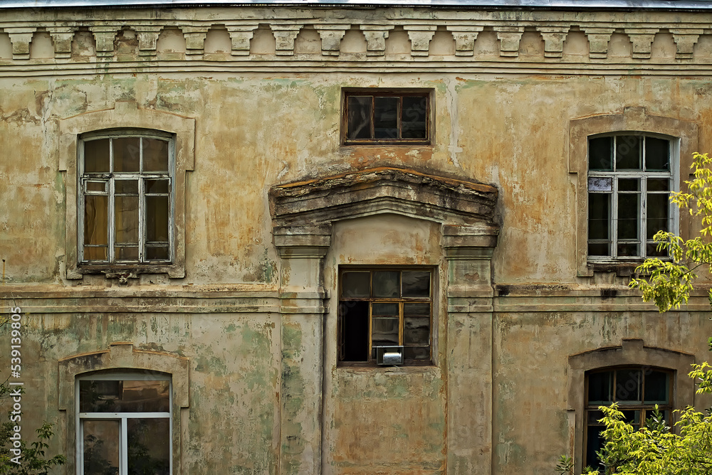 wall of an old house with peeling plaster. the house was built during the time of tsarist russia.