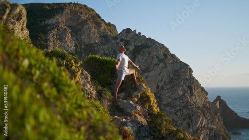 Man practicing yoga asana at stunning ocean cliff view. Focused athlete exercise