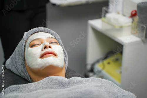Closeup beauty woman with white mask cream on her face in beauty clinic.