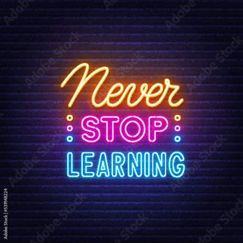 Never Stop Learning neon quote on a brick wall.
