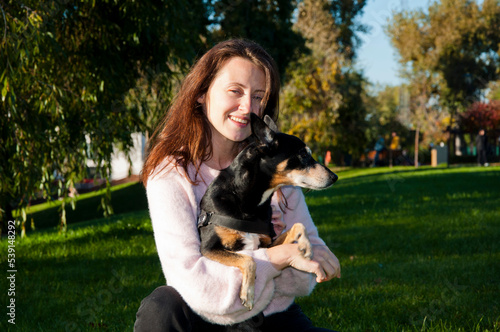 smiling girl embracing dog in autumn park outdoor. friendship of girl and dog. girl adopt dog