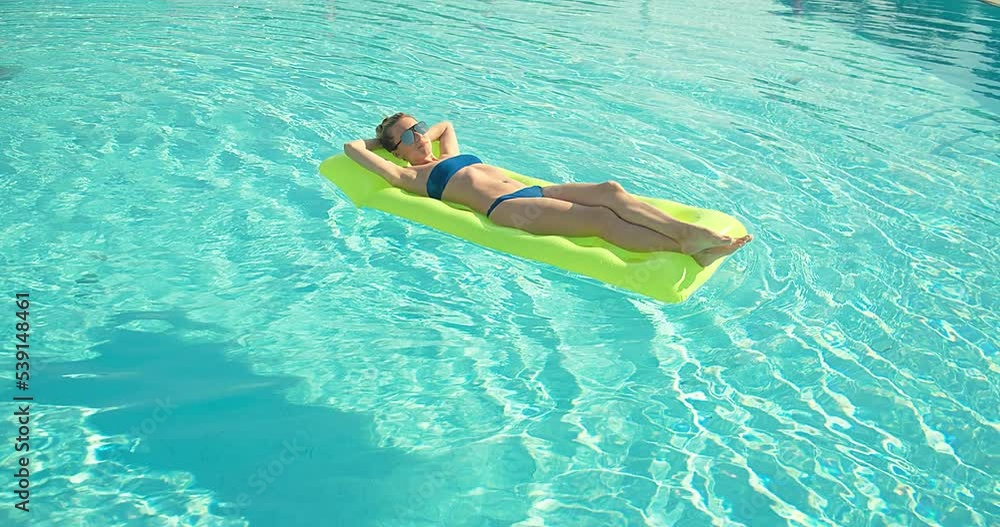 Woman sunbathes in the pool, swimming on the air mattress in hot summer day. Relax, Travel, Holidays, Freedom concept. 4K slow motion Woman sunbathes in the pool, swimming on the air mattress in hot summer day. Relax, Travel, Holidays, Freedom concept. 4K slow motion