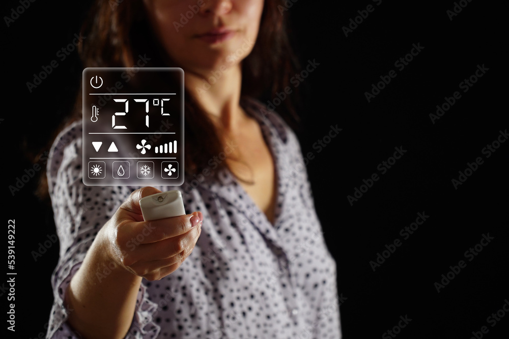 A woman in pajamas sets the temperature in the heating and air conditioning system of a bedroom, apartment or house. User interface on virtual screen. A woman in pajamas sets the temperature in the heating and air conditioning system of a bedroom, apartment or house. User interface on virtual screen.