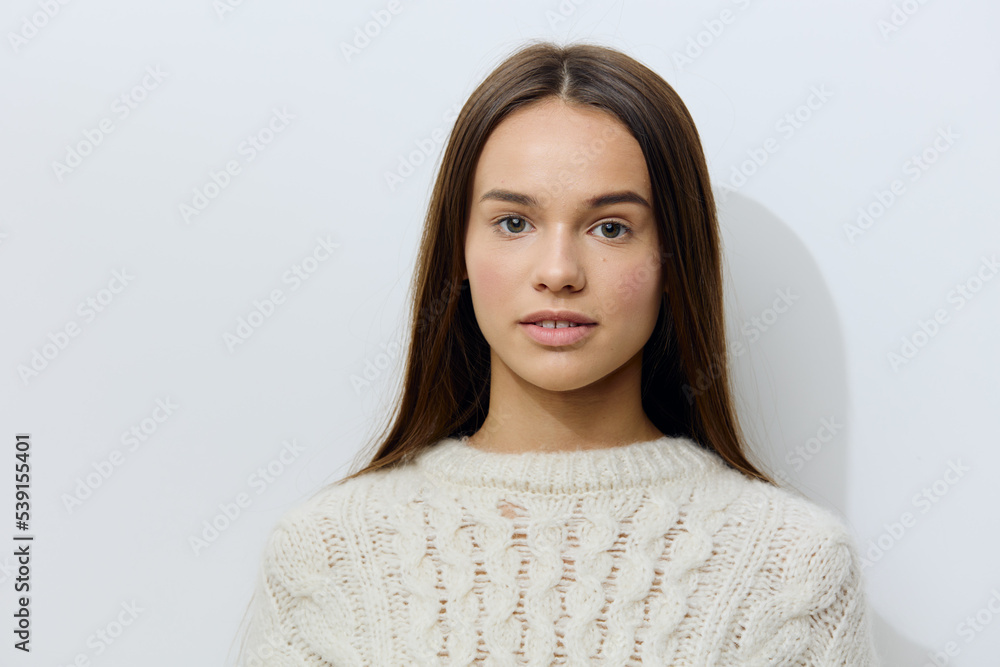 attractive, young woman stands in a white stylish sweater on a light background pleasantly looking at the camera with well-groomed hair attractive, young woman stands in a white stylish sweater on a light background pleasantly looking at the camera with well-groomed hair