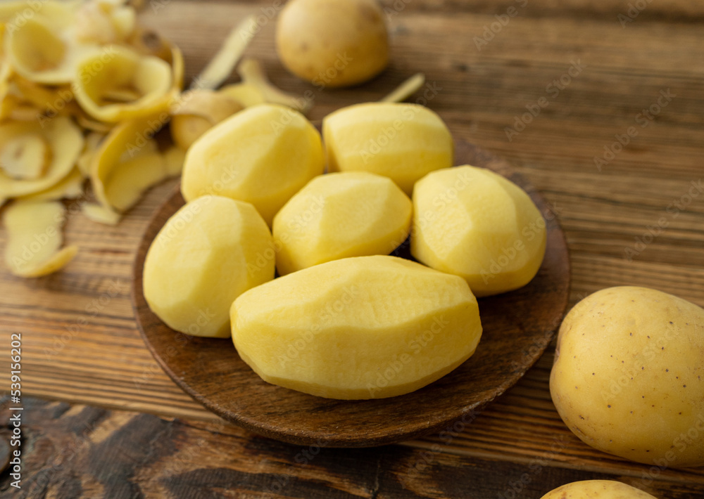 Peeling and Slicing Potatoes on Wooden Cutting Board Peeling and Slicing Potatoes on Wooden Cutting Board