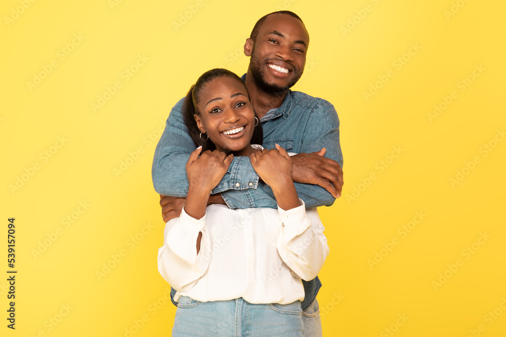 Loving African American Spouses Hugging Posing On Yellow Studio Background Loving African American Spouses Hugging Posing On Yellow Studio Background