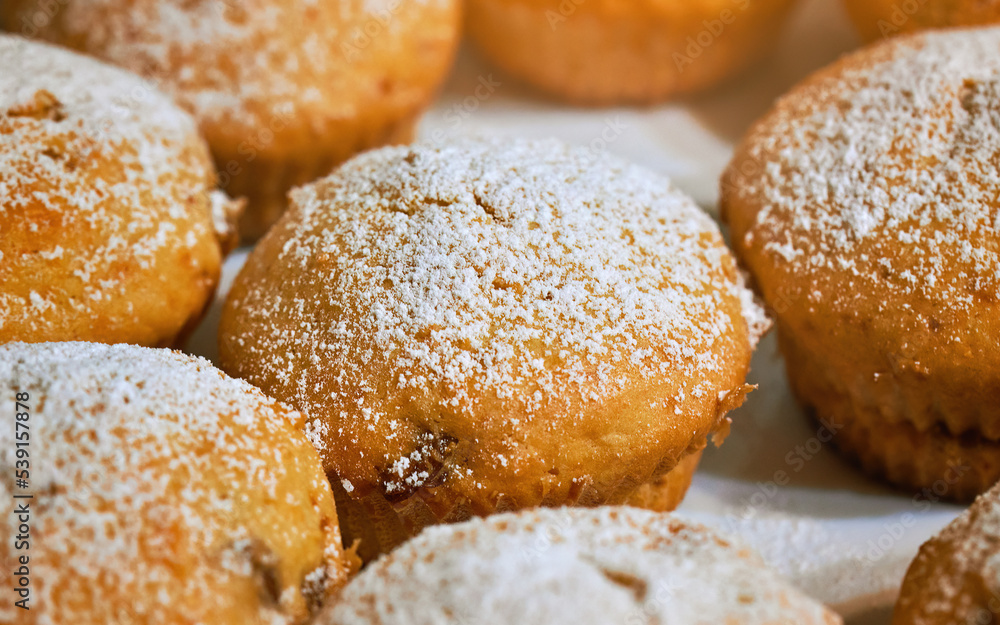 Muffins with powdered sugar. Fresh baked hommeda muffins. Cupcakes sprinkled with powdered sugar, tasty cake