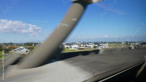 Look out to Japanese outskirts from fast bullet train, riding from Tokyo to Utsunomiya. Detached houses and green fields seen outdoors. High speed vehicle rush across country photo