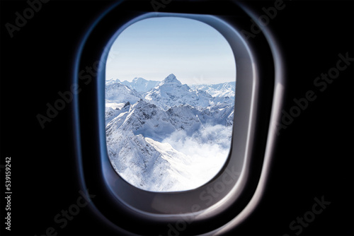 Mountains iew through a jet plane window high on the blue sky photo