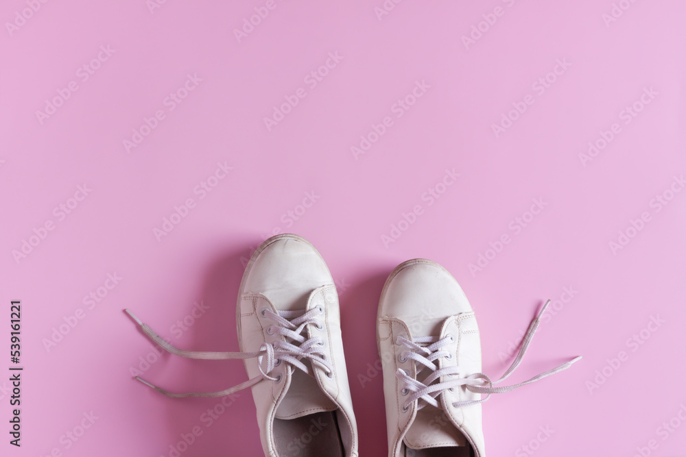 White leather sneakers isolated on pink background, Women's shoes, Fashionable casual shoes.