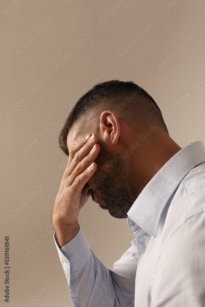 Stressed young bearded man covers his face posing on white background. Stressed young bearded man covers his face posing on white background.