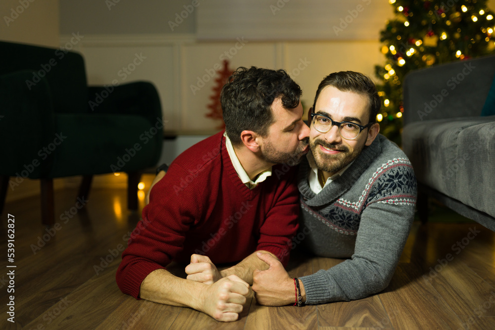 Gay man kissing his partner while relaxing on christmas Gay man kissing his partner while relaxing on christmas