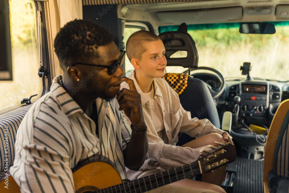 Types of friendships and relationships. Young couple of different ethnic background sitting together on van sofa, and listening to the other friends. Planning new journey. High quality photo